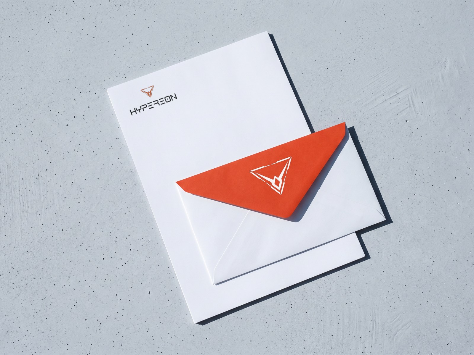 A render of a Hypereon letterhead on concrete with a white envelope across it, its orange flap carrying the mark in white