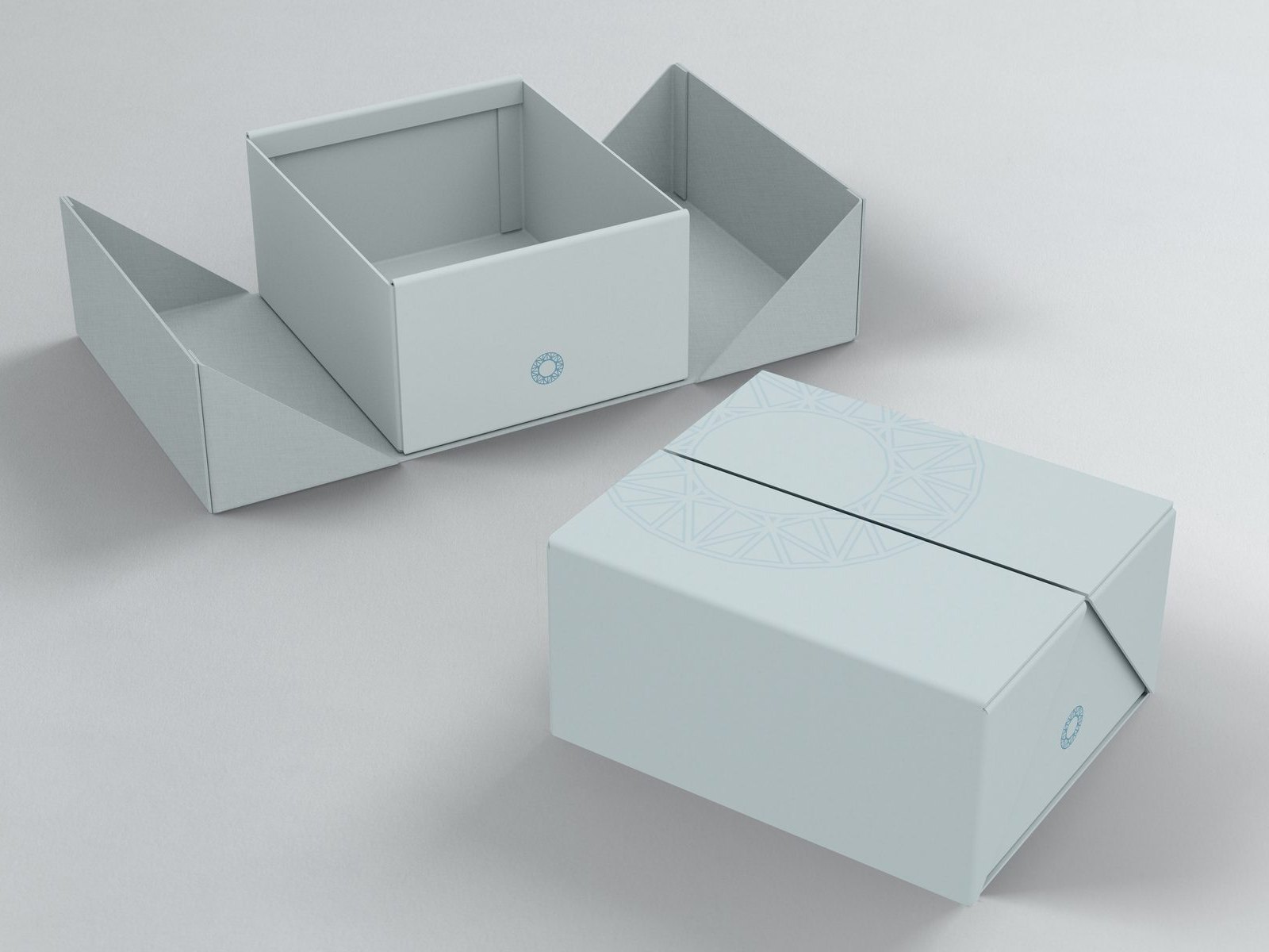 An open pale blue shipping box beside a closed one, the ornament printed in tone