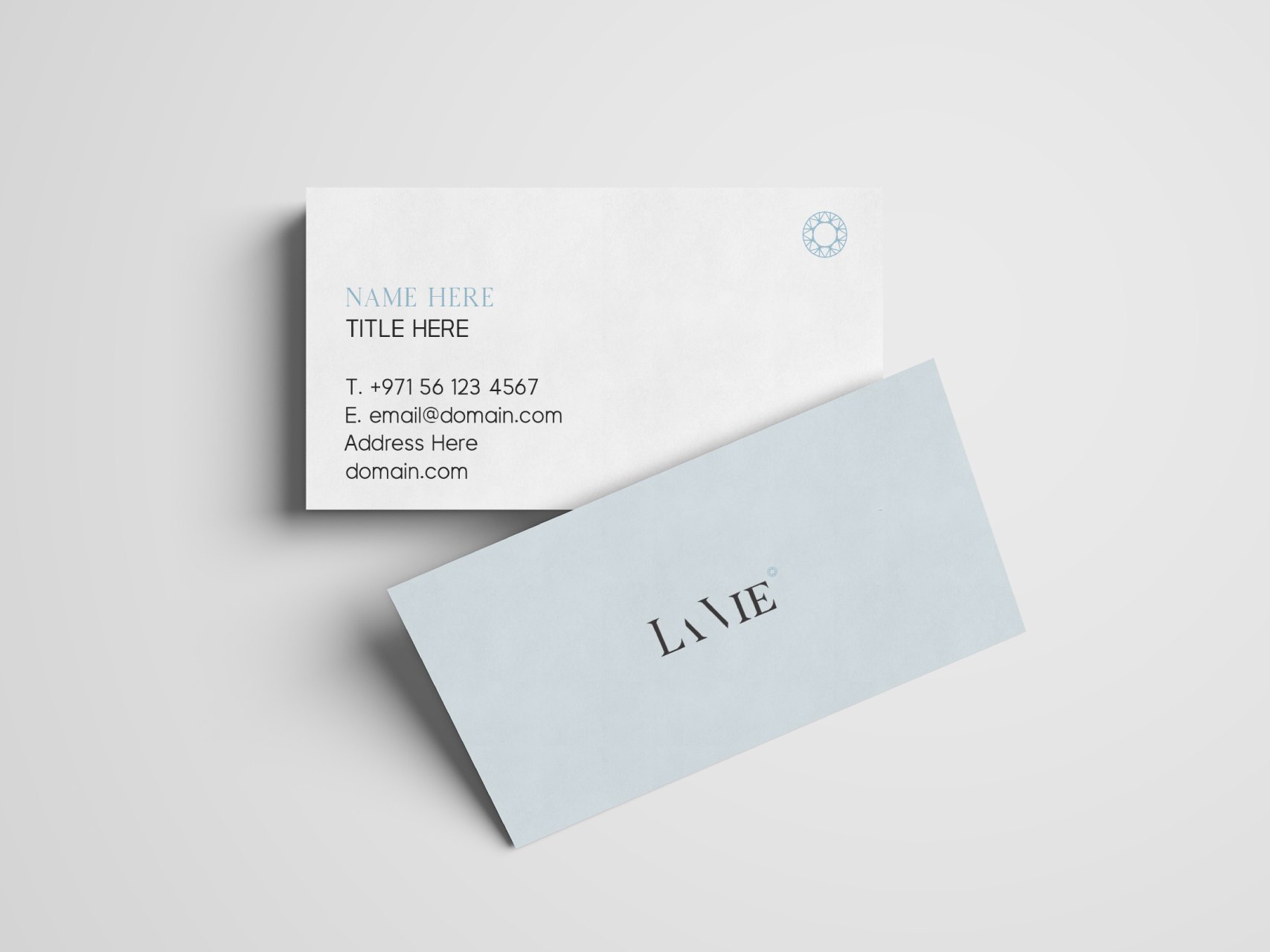 Two La Vie business cards, one white with the ornament, one pale blue with the wordmark