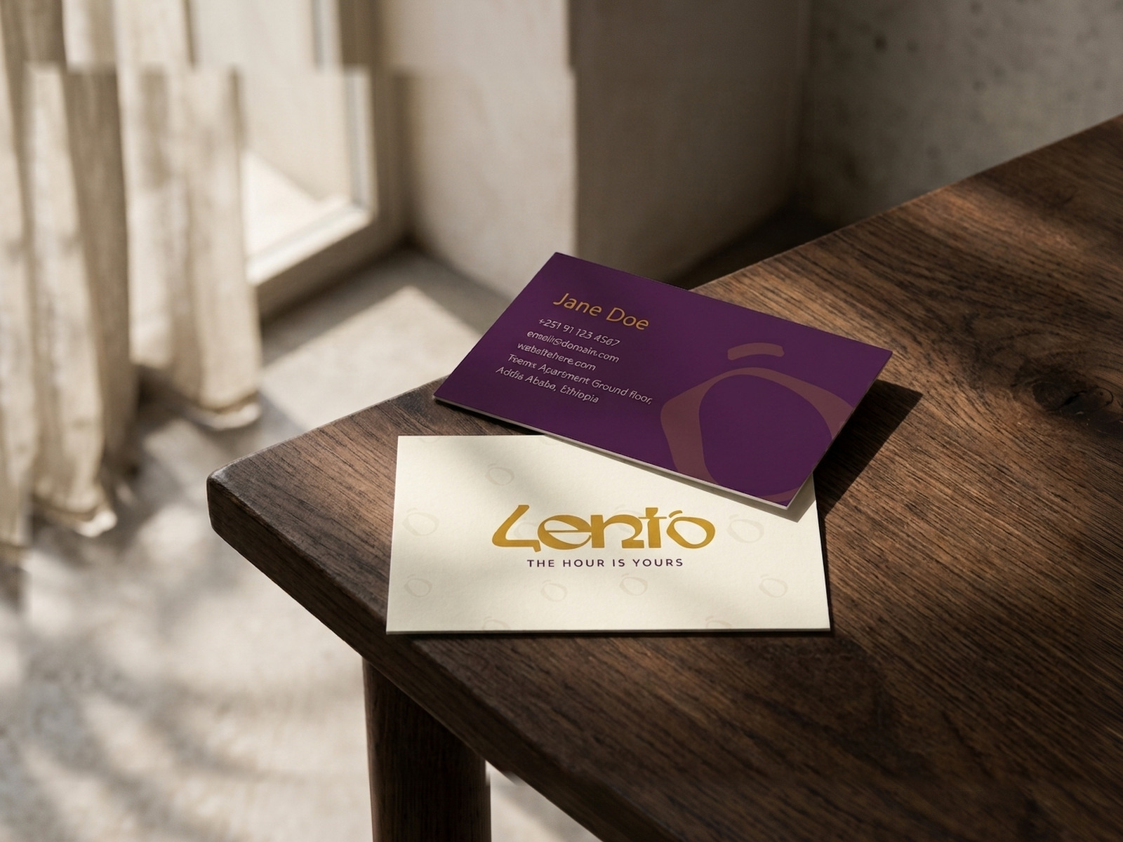 Lento business cards, one plum and one cream, on a wooden table