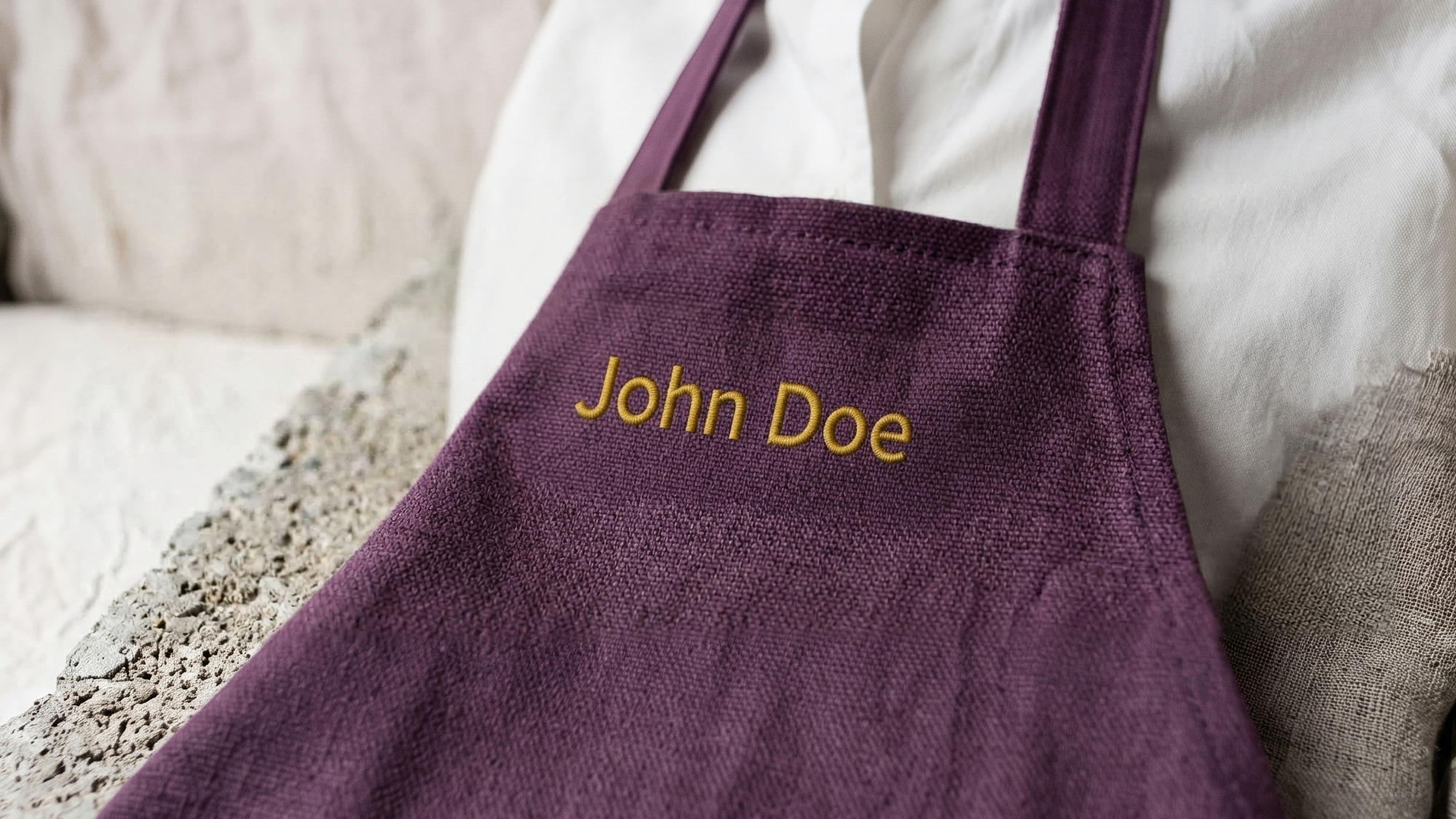 The plum Lento apron with a name stitched in mustard