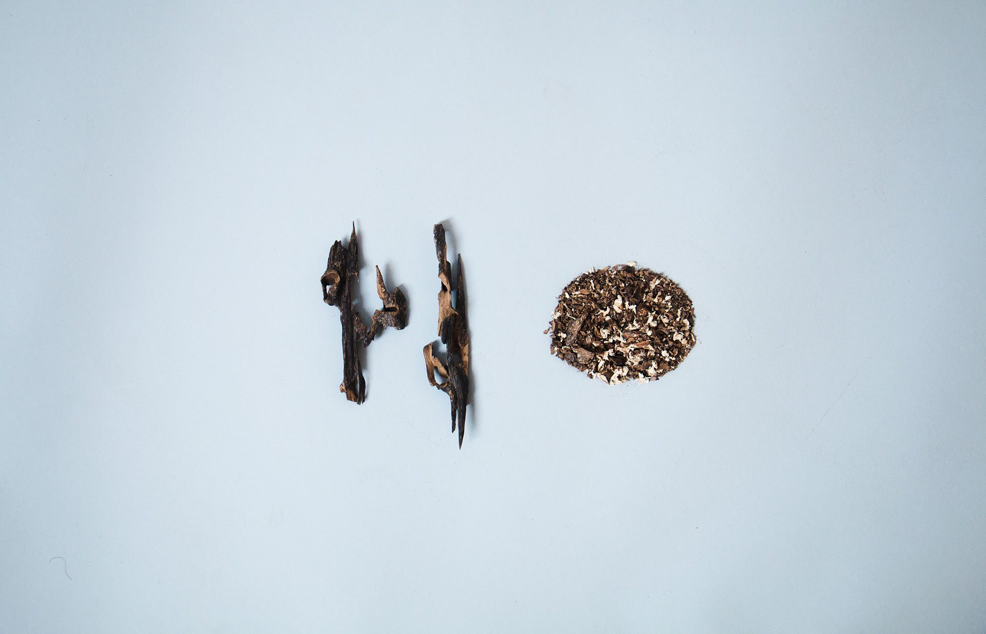 Pieces of agarwood and a round pile of shavings on a pale blue ground