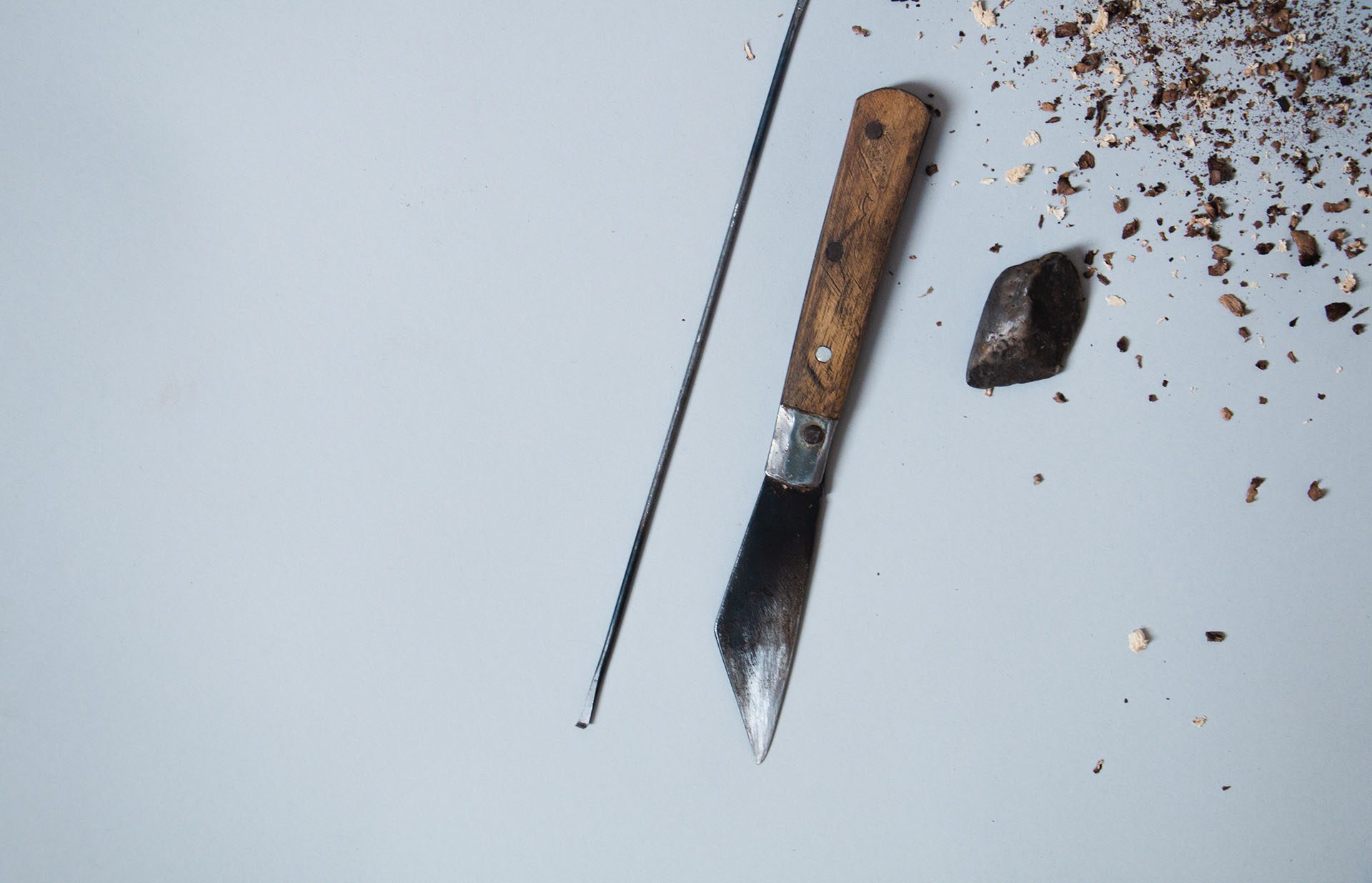 A carving knife, a pick and a piece of agarwood on a pale blue ground