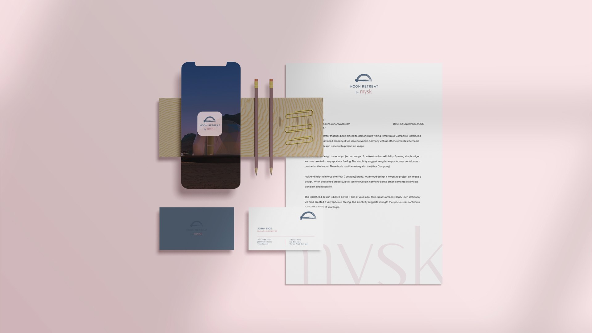 A letterhead, two business cards, pencils and a phone showing the app icon