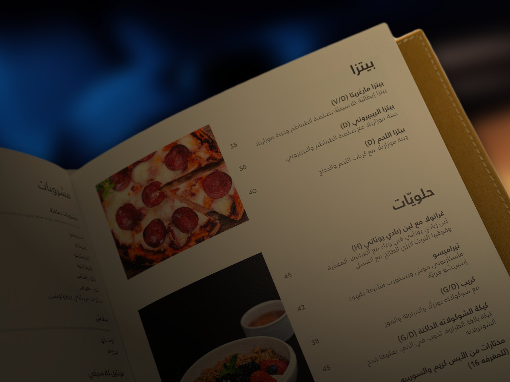 A menu page in Arabic with photographs of a pizza and a dessert, in warm low light