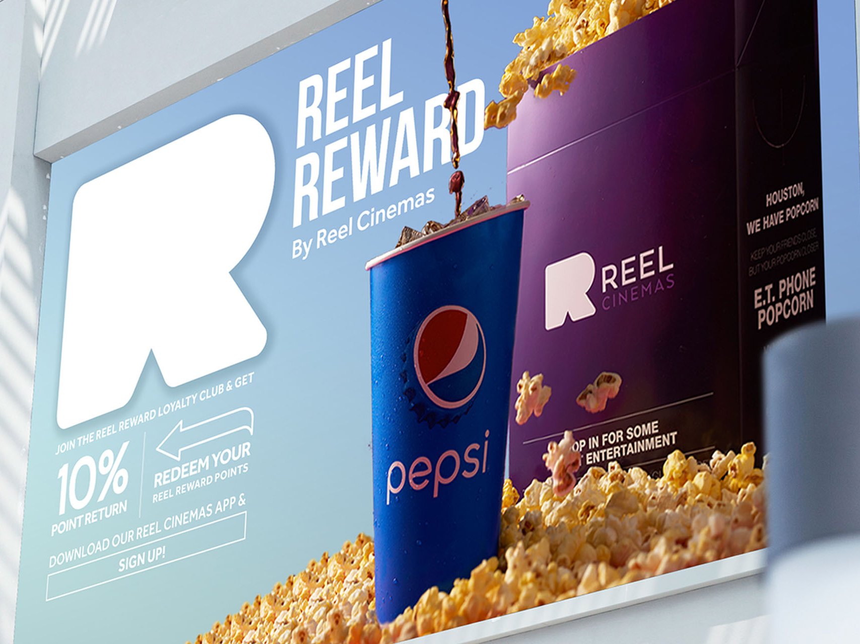A Reel Reward billboard with the large white R, a cup and a popcorn bucket