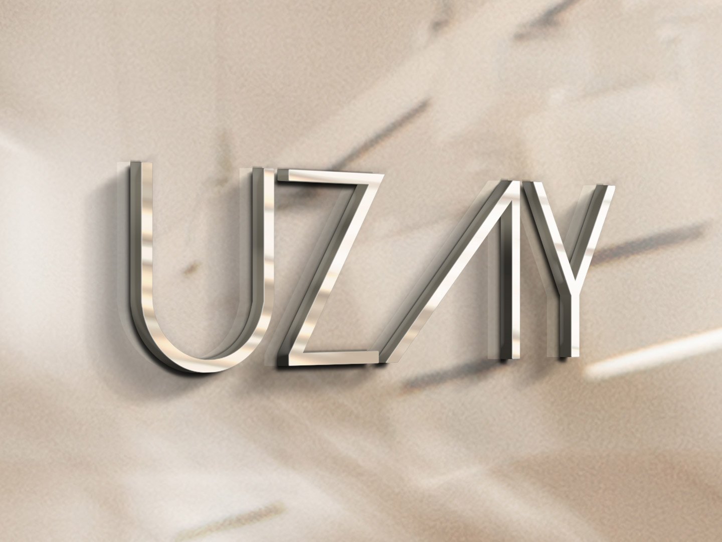The Uzay wordmark in brushed metal letters on a plaster wall