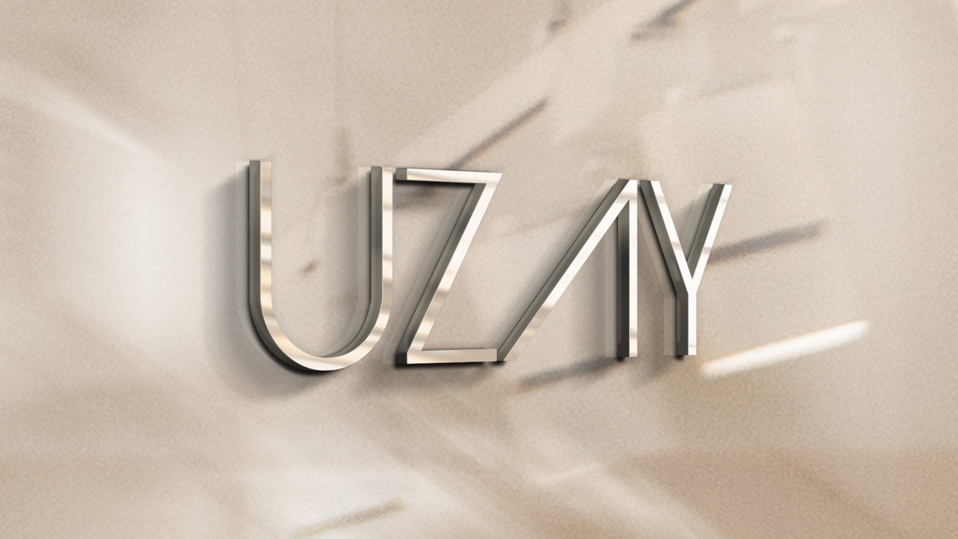 The Uzay wordmark as brushed metal letters on a warm plaster wall in raking light